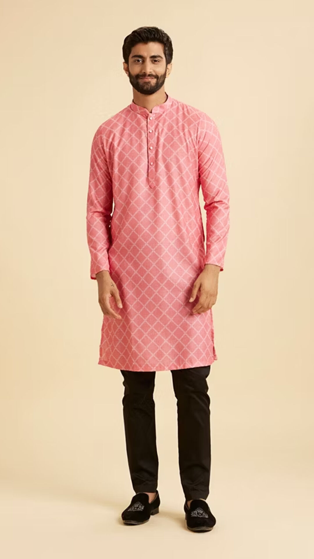 A stylish man modeling a modern peach-colored kurta with a diamond pattern and dark trousers